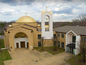 A modern church building with a golden dome and bell tower.
